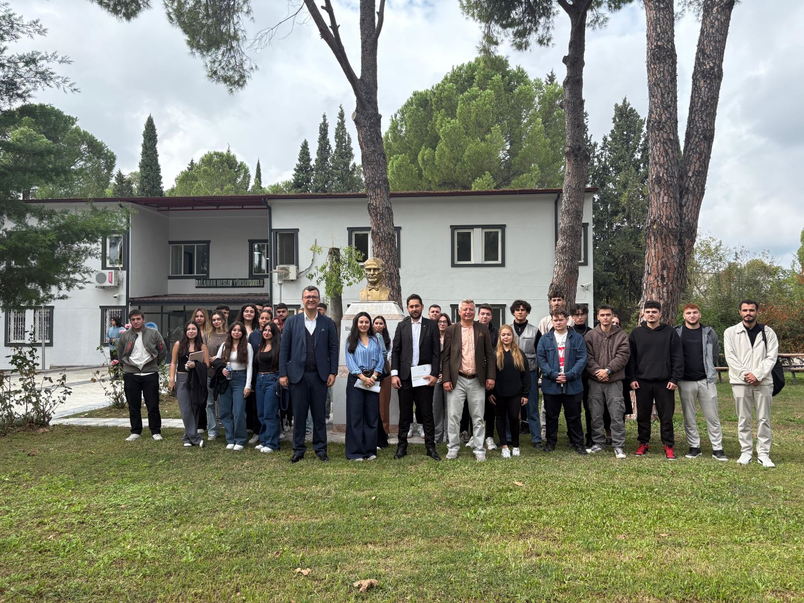 “Alumni–Student Meeting conference held in a Dalaman Vocational School classroom. An Atatürk portrait and a projection screen are visible in the background. Kudret Hasgül is giving a presentation while students and faculty members listen attentively. Event dated 23 October 2025.”